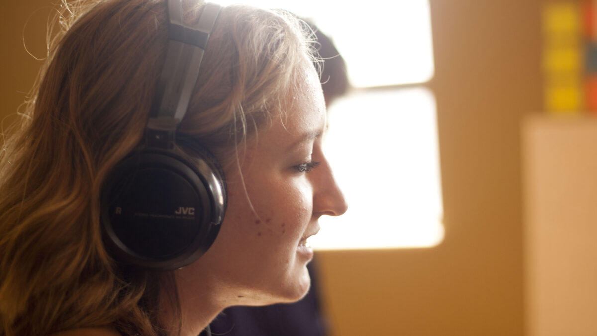 A teen wearing headphones in a gold-colored room