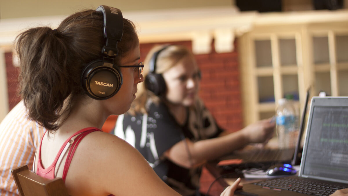 Two teens wearing headphones looking at laptop computers
