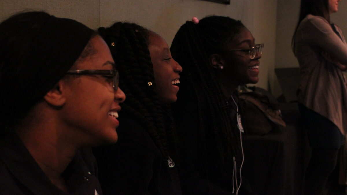 Three youth smiling while sitting facing to the right