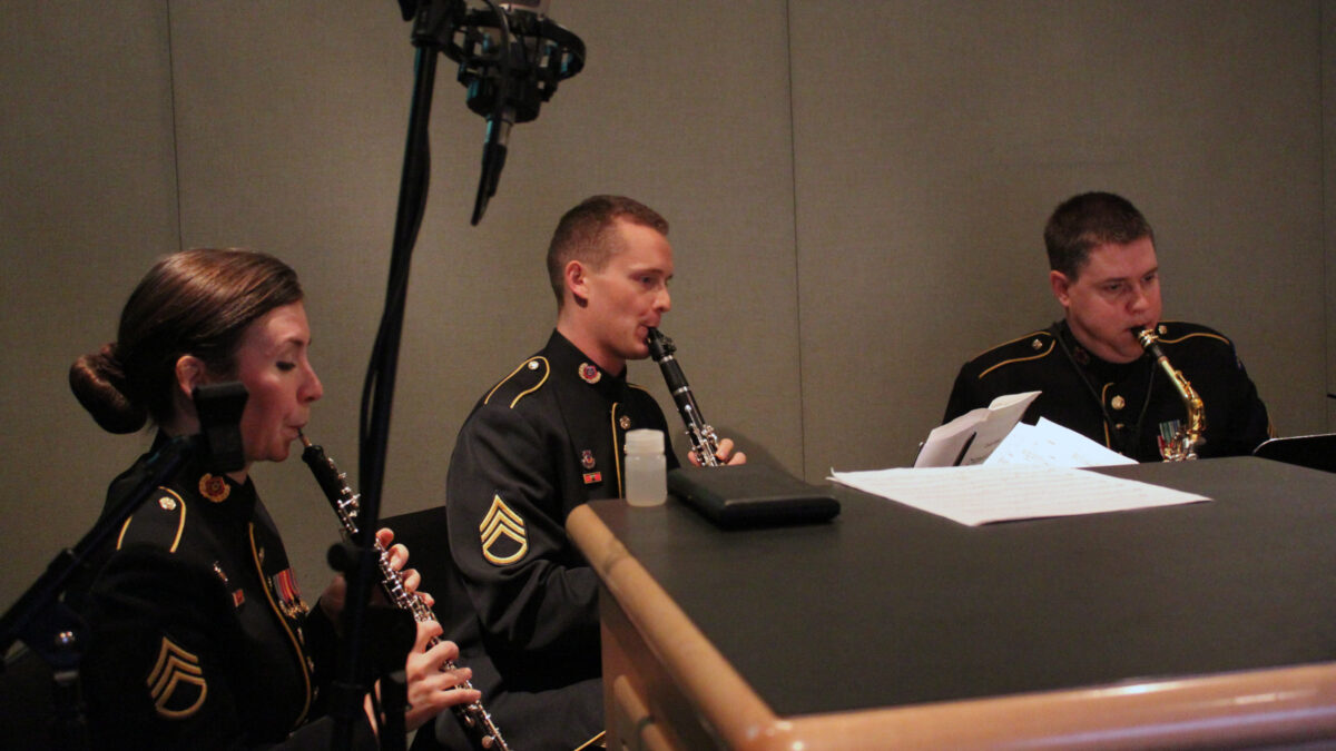 An adult playing oboe, an adult playing clarinet, and an adult playing alto saxophone in a radio studio
