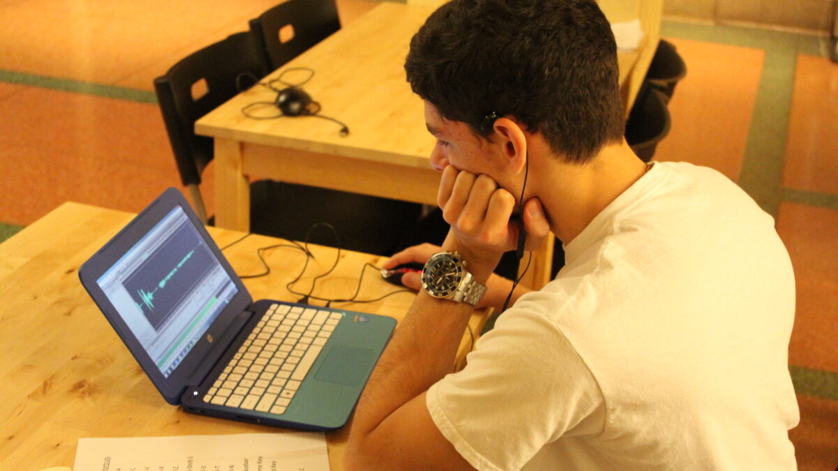 A youth looking at a laptop computer on a wooden table