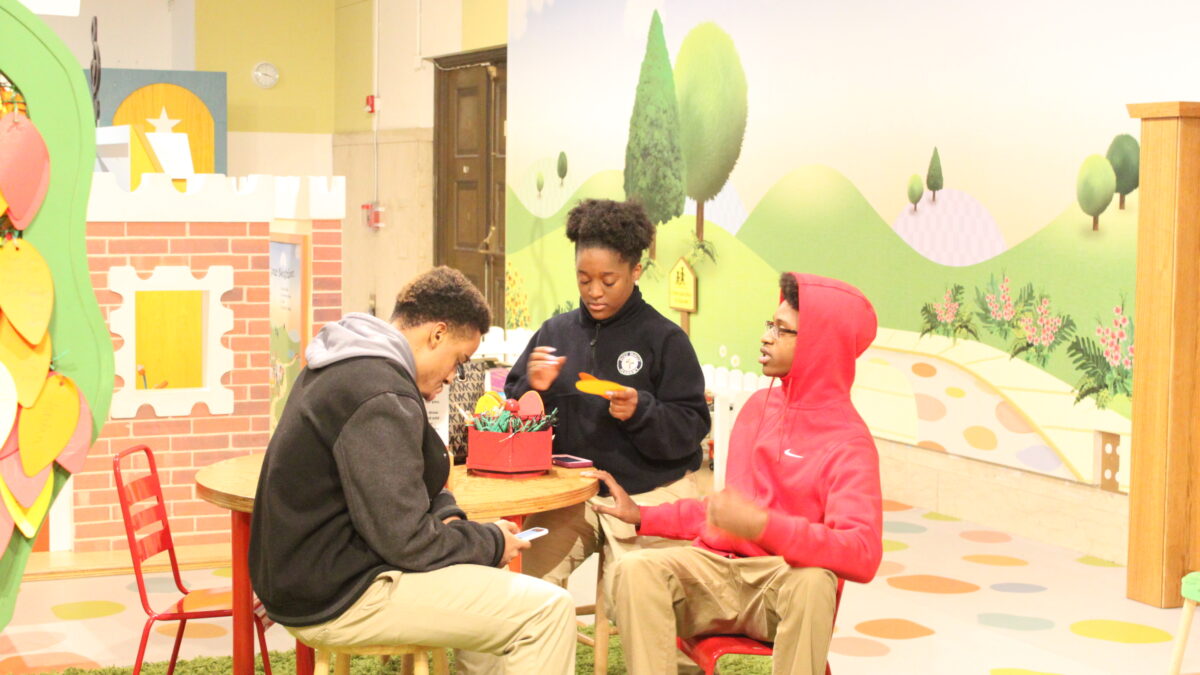 Three teens sitting around a round wooden table