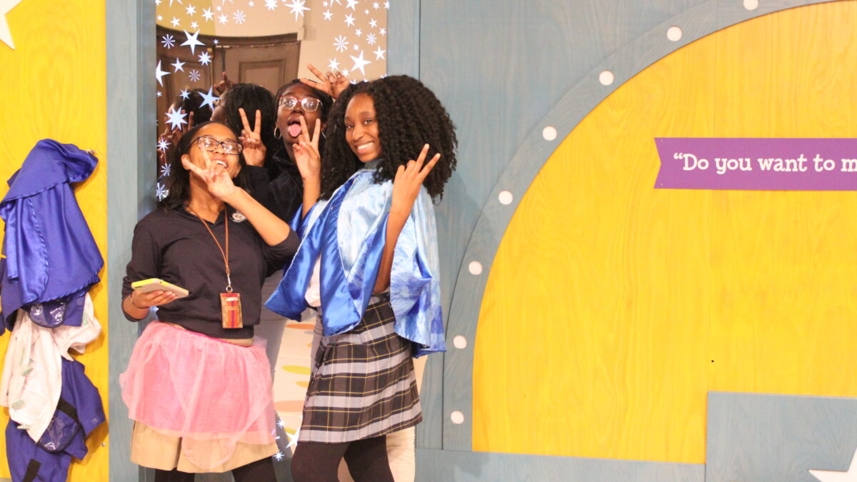 Three teens posing in front of a gray museum exhibit