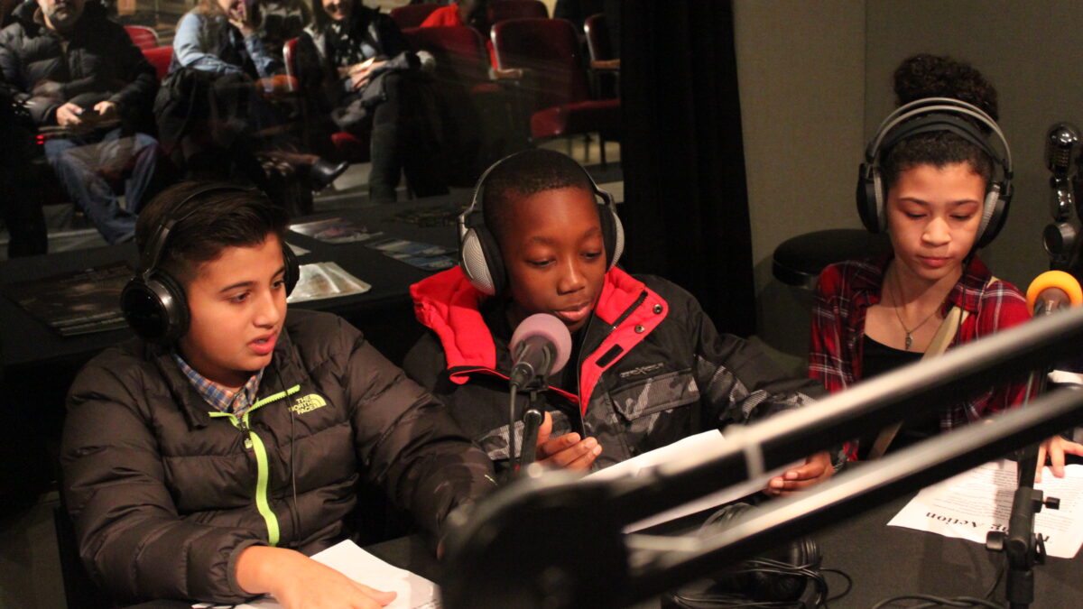 Three youth wearing headphones speaking into microphones in a radio studio