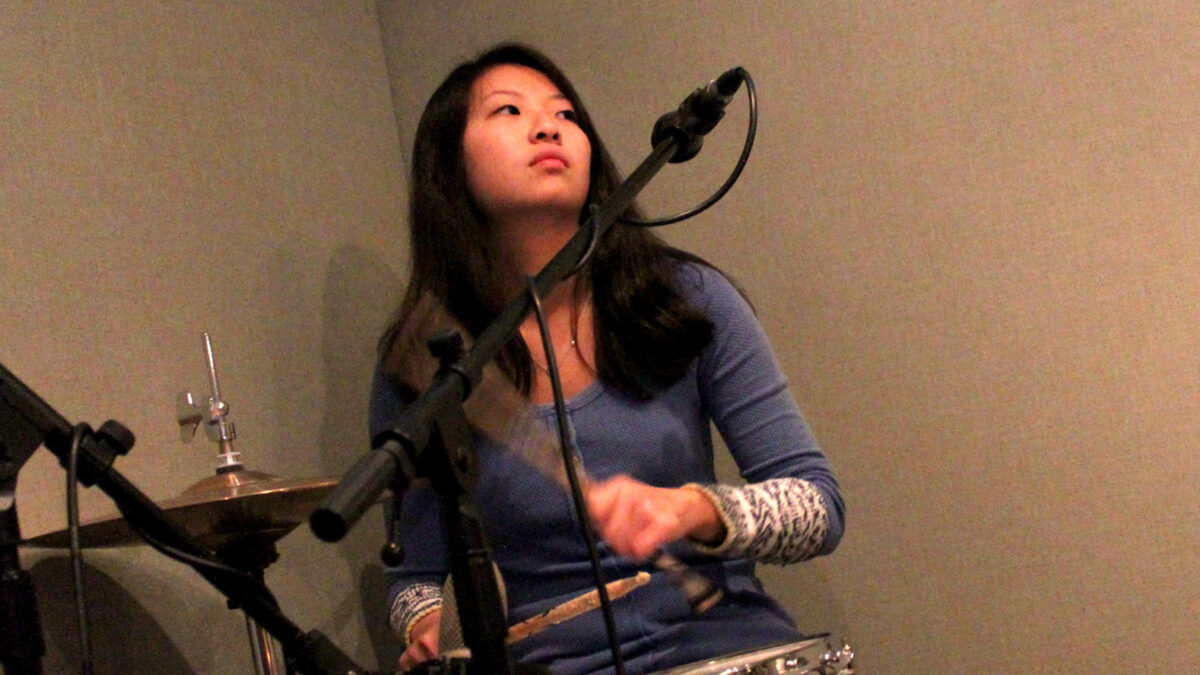 A teen playing a drum set in a radio studio