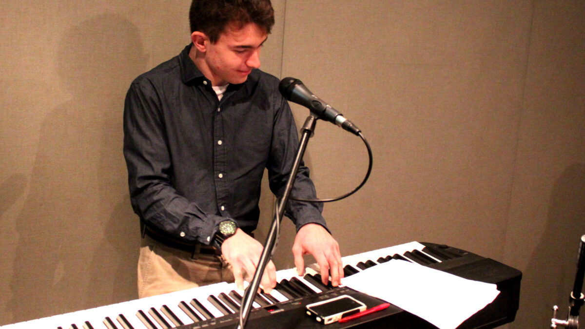 A teen playing a piano keyboard in a radio studio