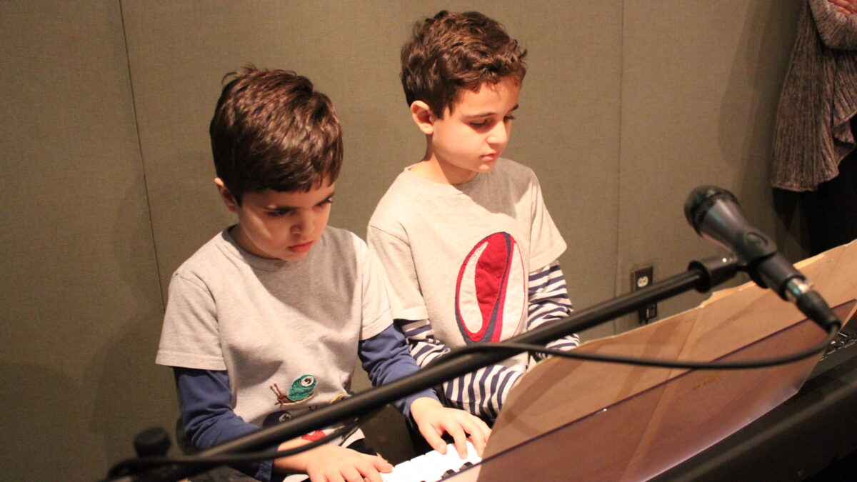 Two youth playing a piano keyboard in a radio studio