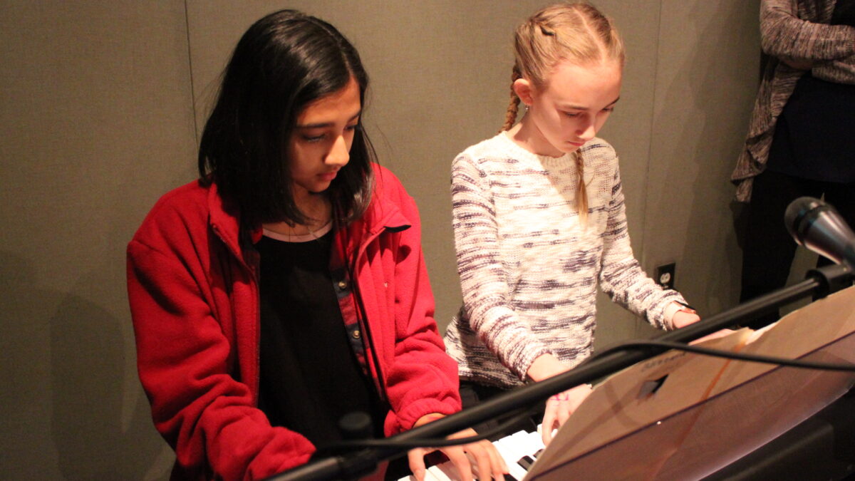 Two youth playing a piano keyboard in a radio studio