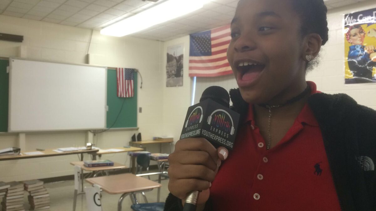A youth speaking into a microphone in a classroom
