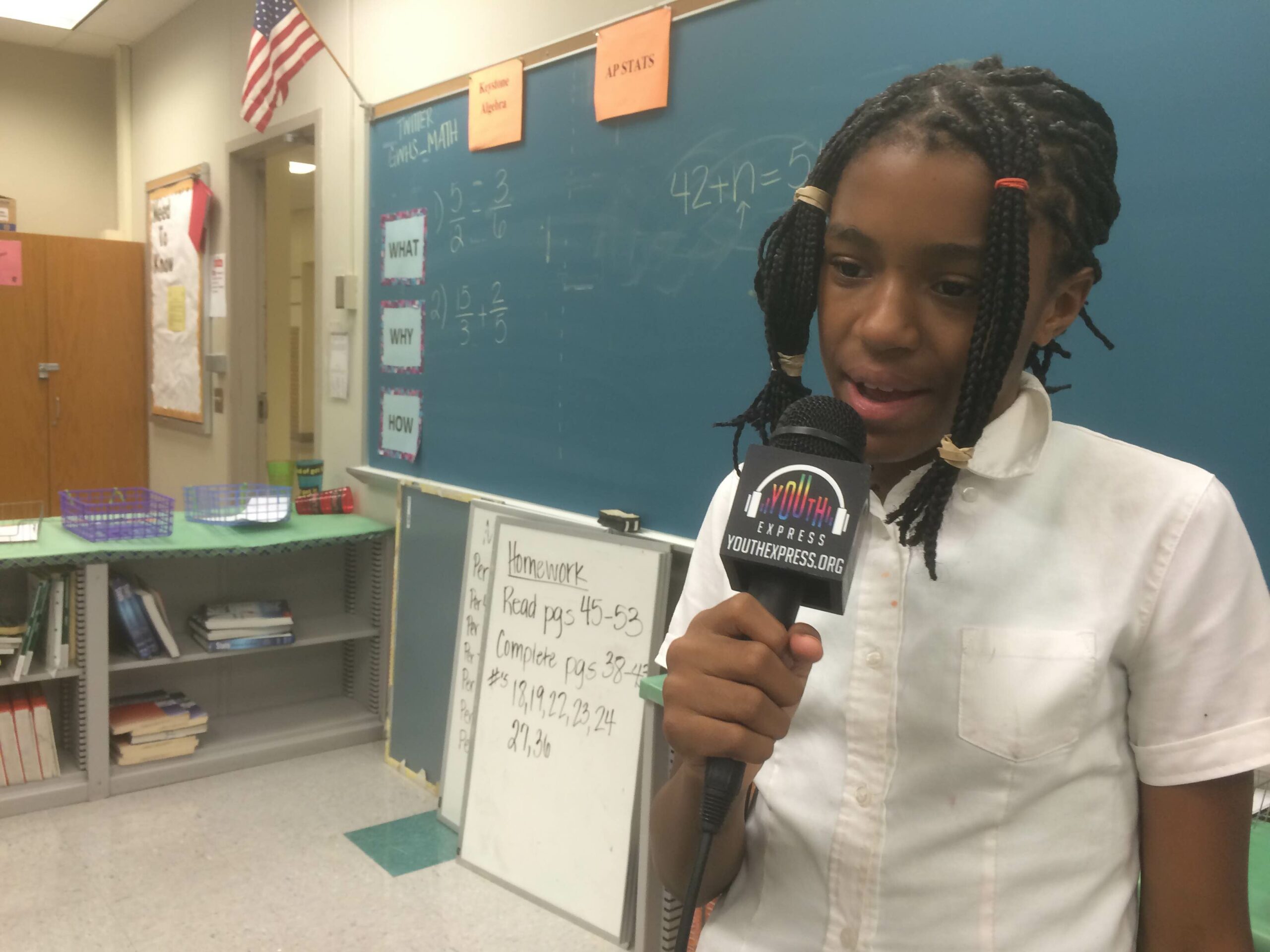 A youth holding and speaking into a microphone in a classroom