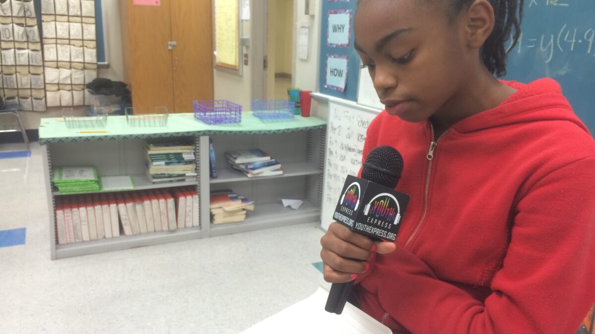 A youth holding a microphone looking down in a classroom
