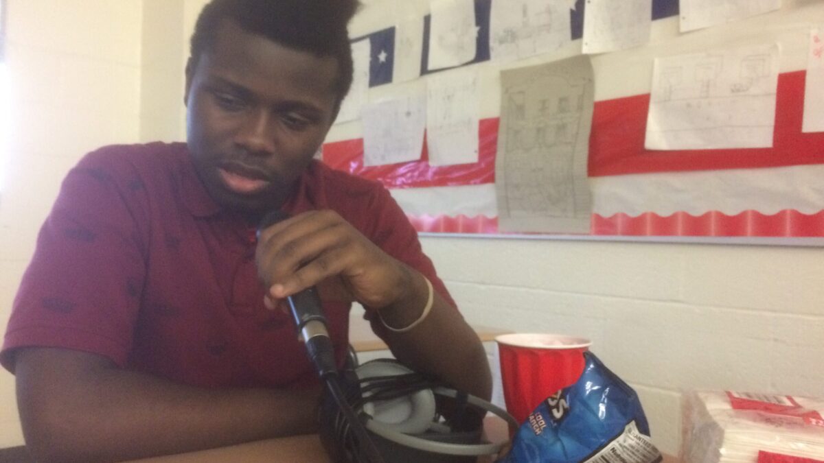 A teen speaking into a microphone in a school cafeteria