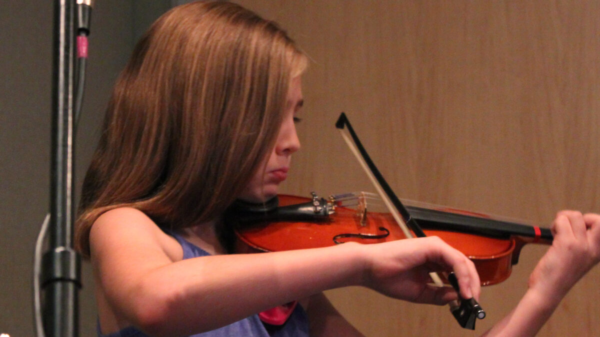 A youth playing a violin in a radio studio