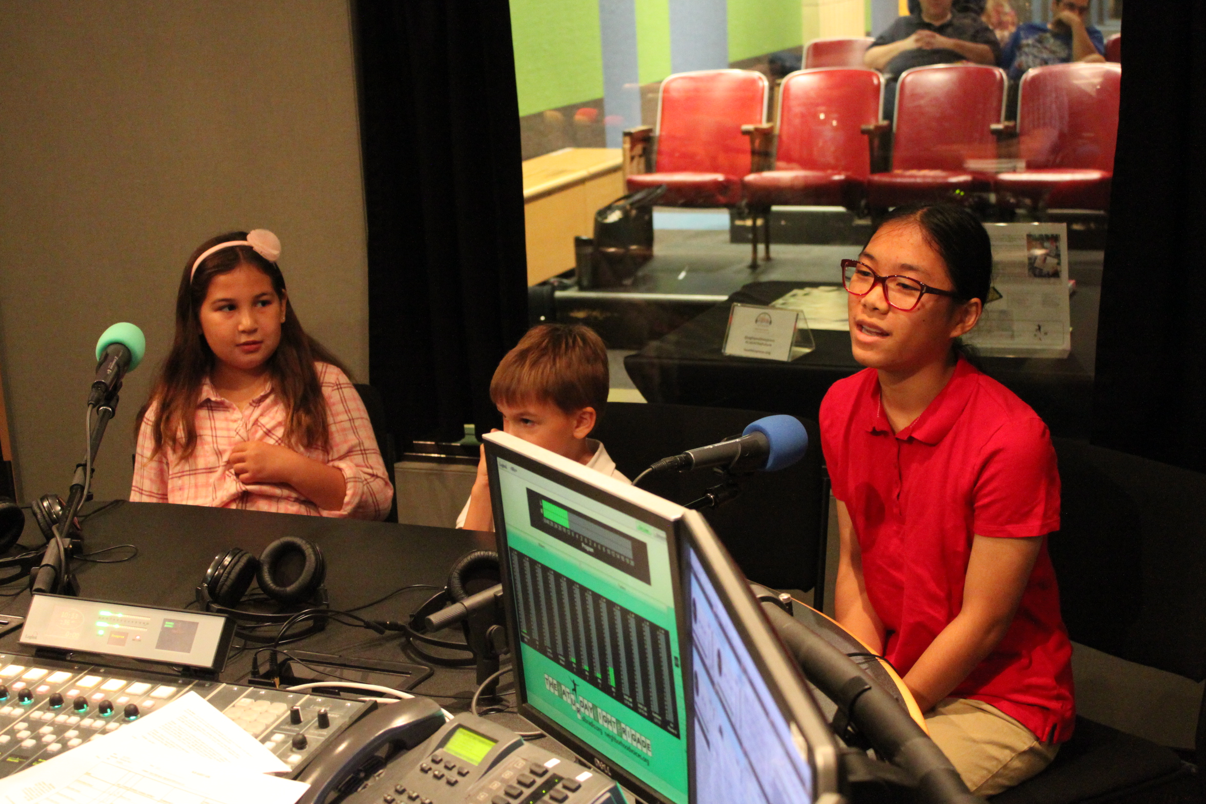 Three youth speaking into microphones in a radio studio