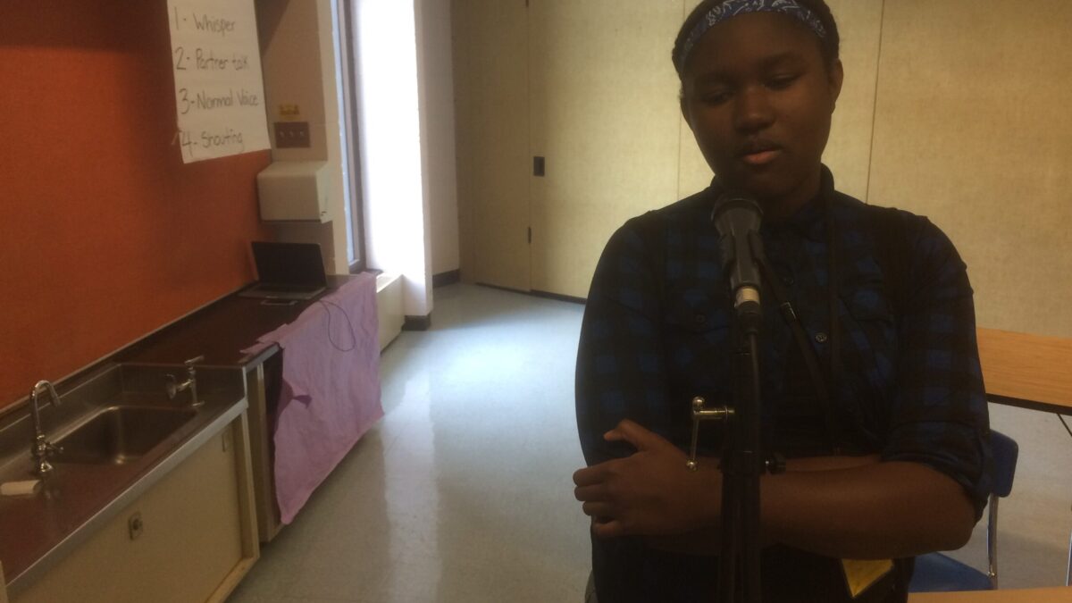 A youth speaking into a microphone in a classroom
