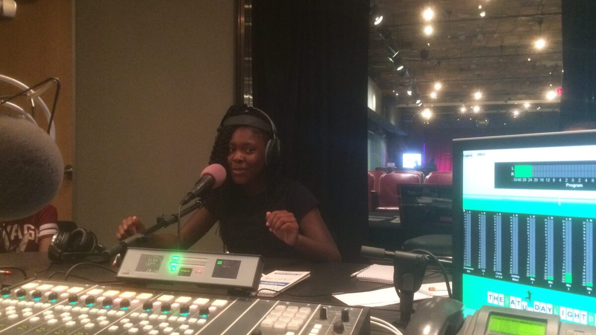 A youth wearing headphones speaking into a microphone in a radio studio
