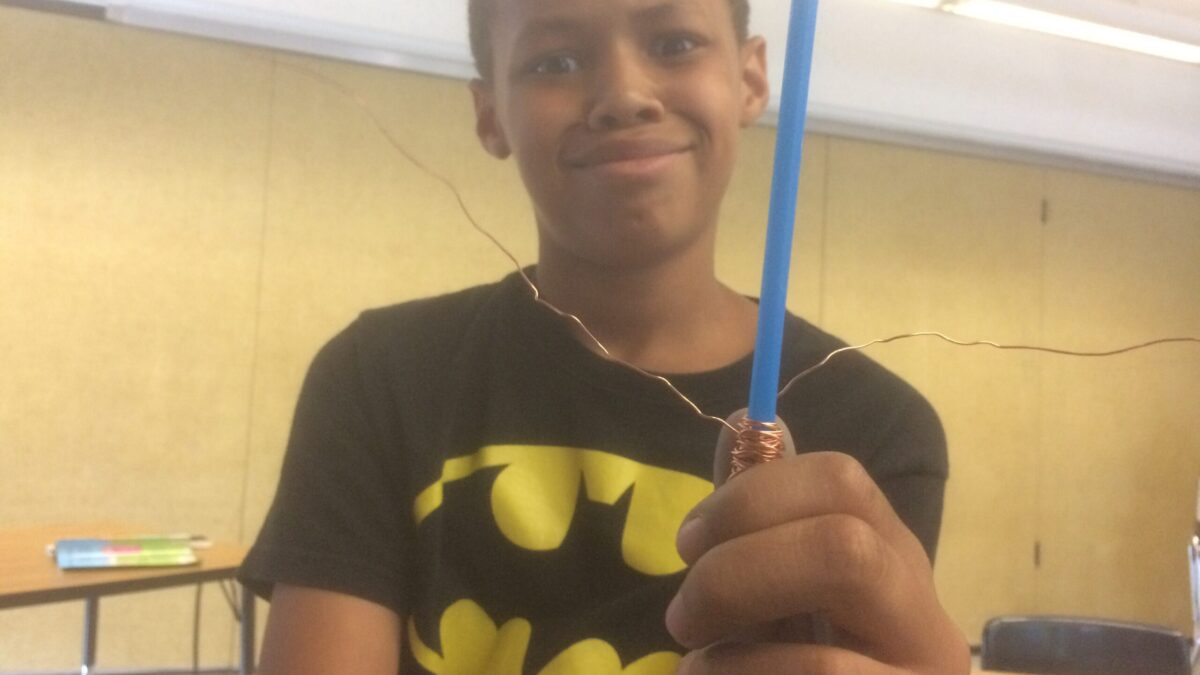 A youth holding a blue pencil and smirking at the camera
