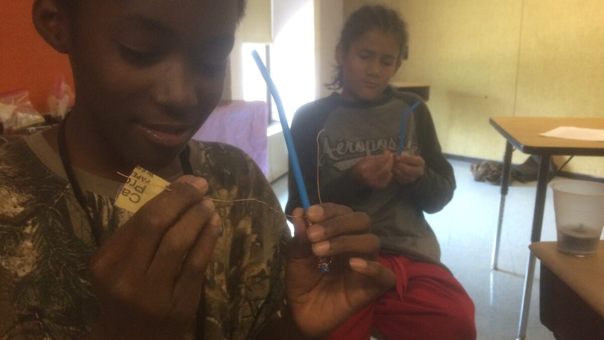 Two youth holding blue pencils in a classroom