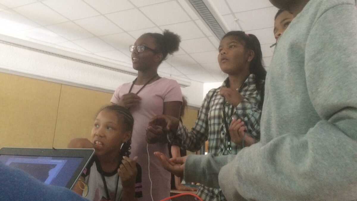 Five youth standing in a classroom looking off into the distance