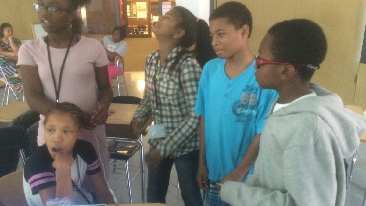 Five youth in a classroom looking off into the distance