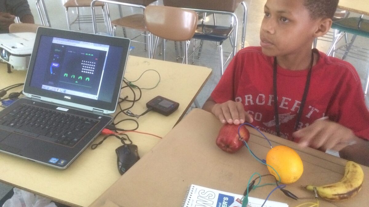 A youth interacting with fruit on a classroom desk.