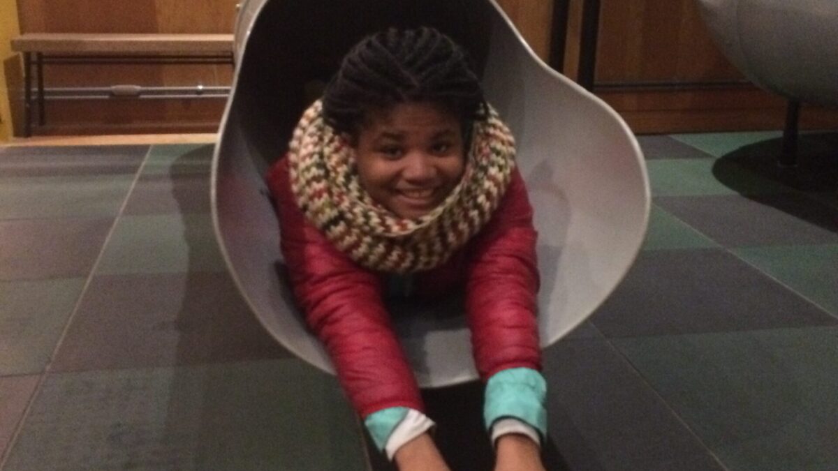 A teen popping out of a metal slide