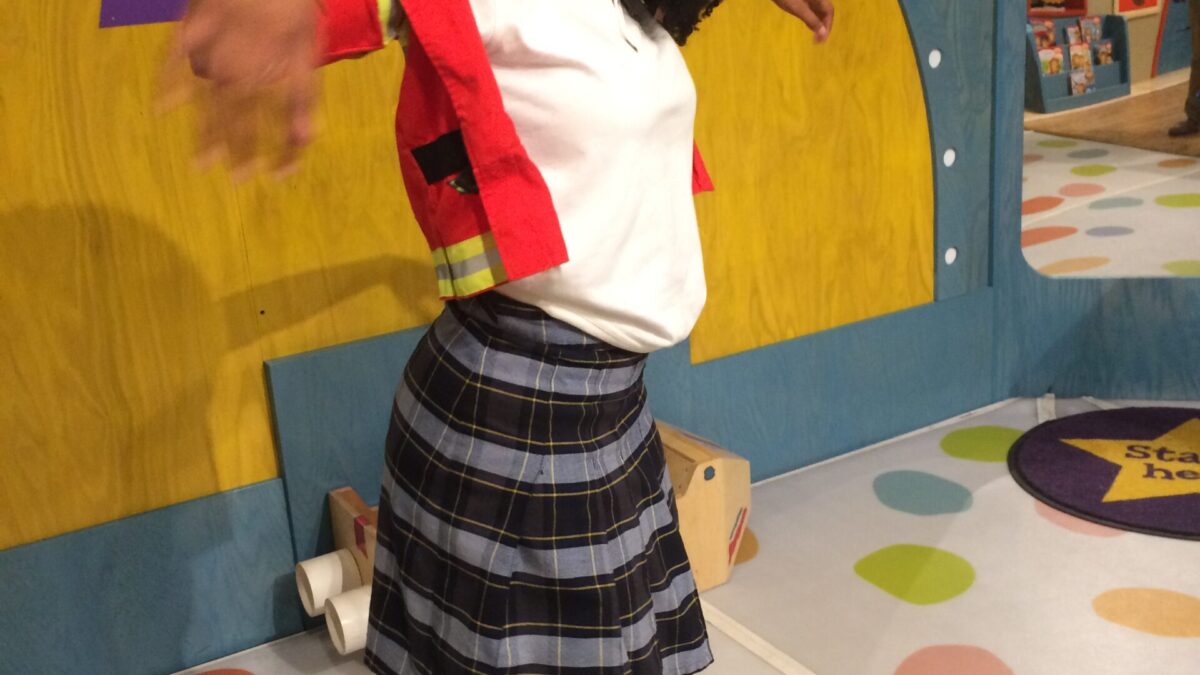 A teen smiling and posing in front of a museum exhibit