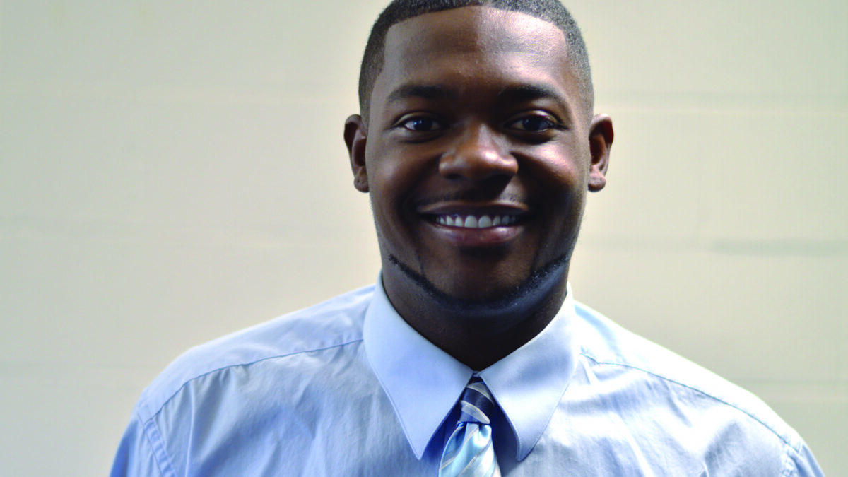 An adult wearing a light blue shirt smiling in profile