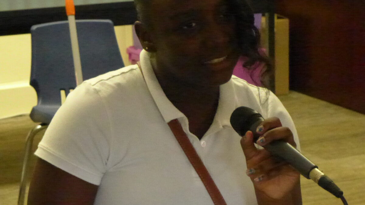A youth holding and speaking into a microphone in a classroom