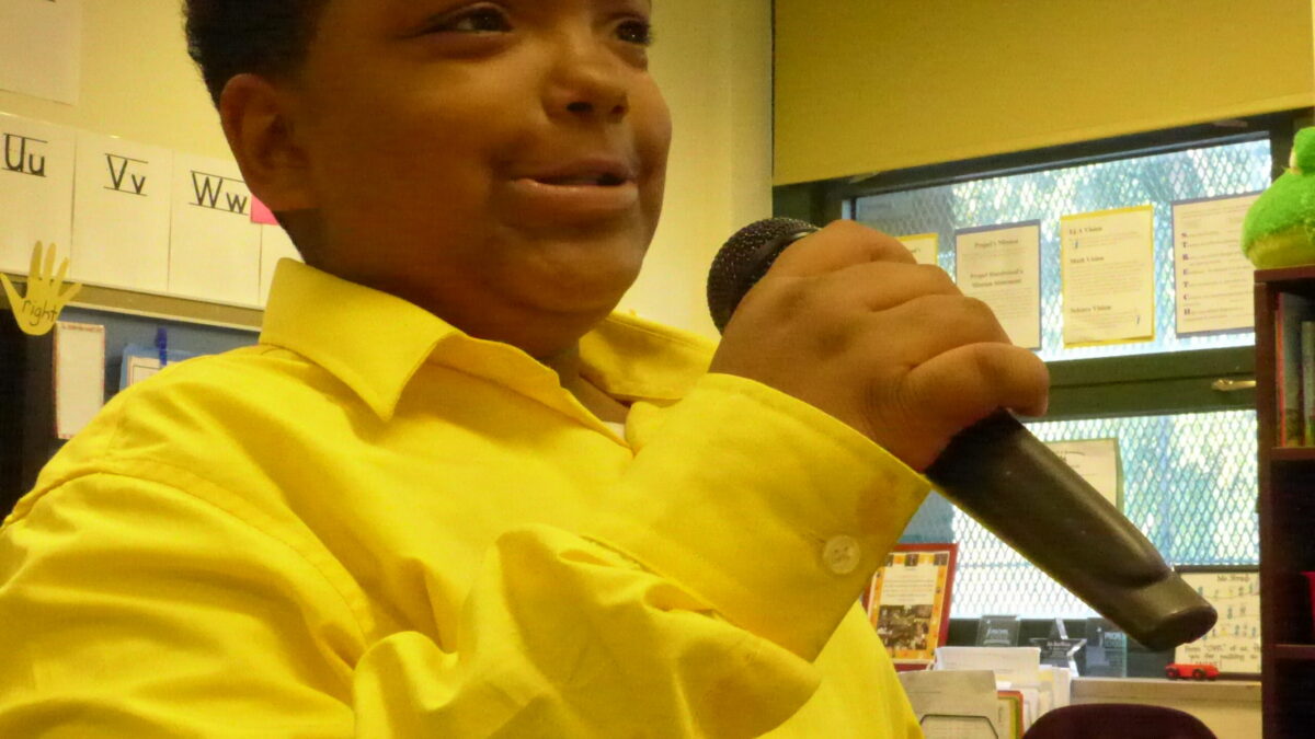 A youth speaking into a microphone in a classroom