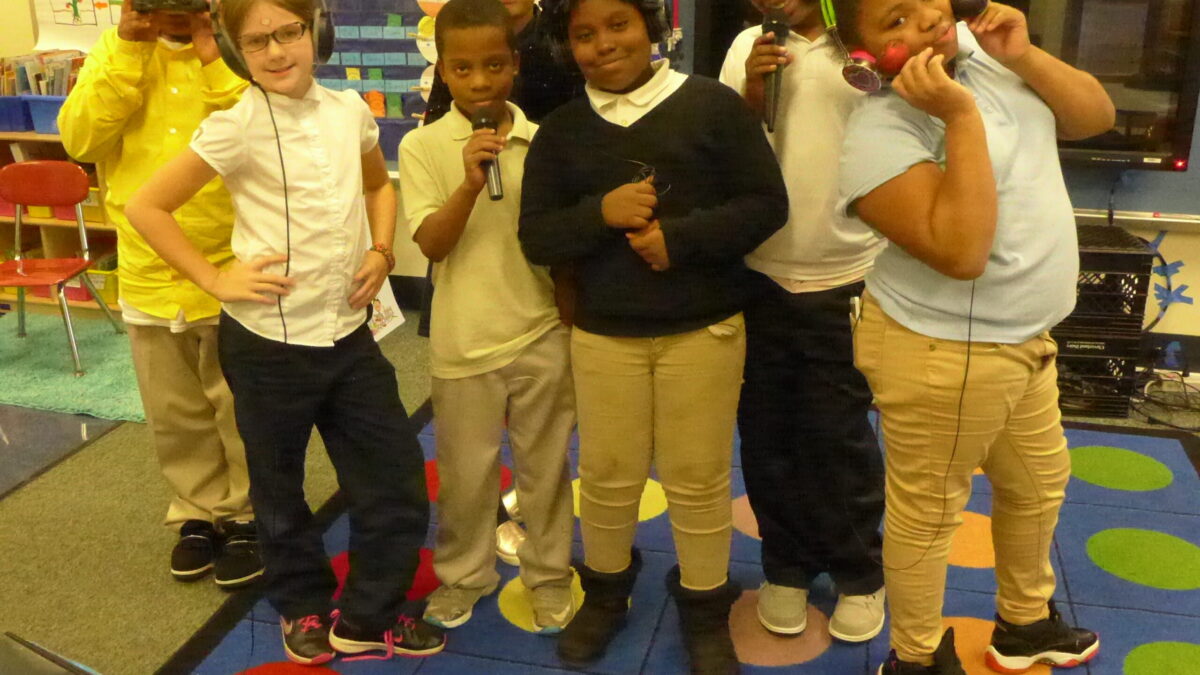 Seven youth smiling and posing in profile, three wearing headphones