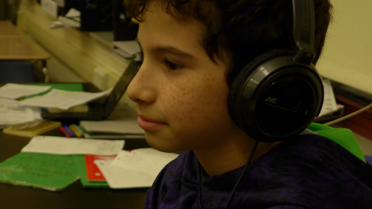 A youth wearing headphones looking off to the side in a classroom