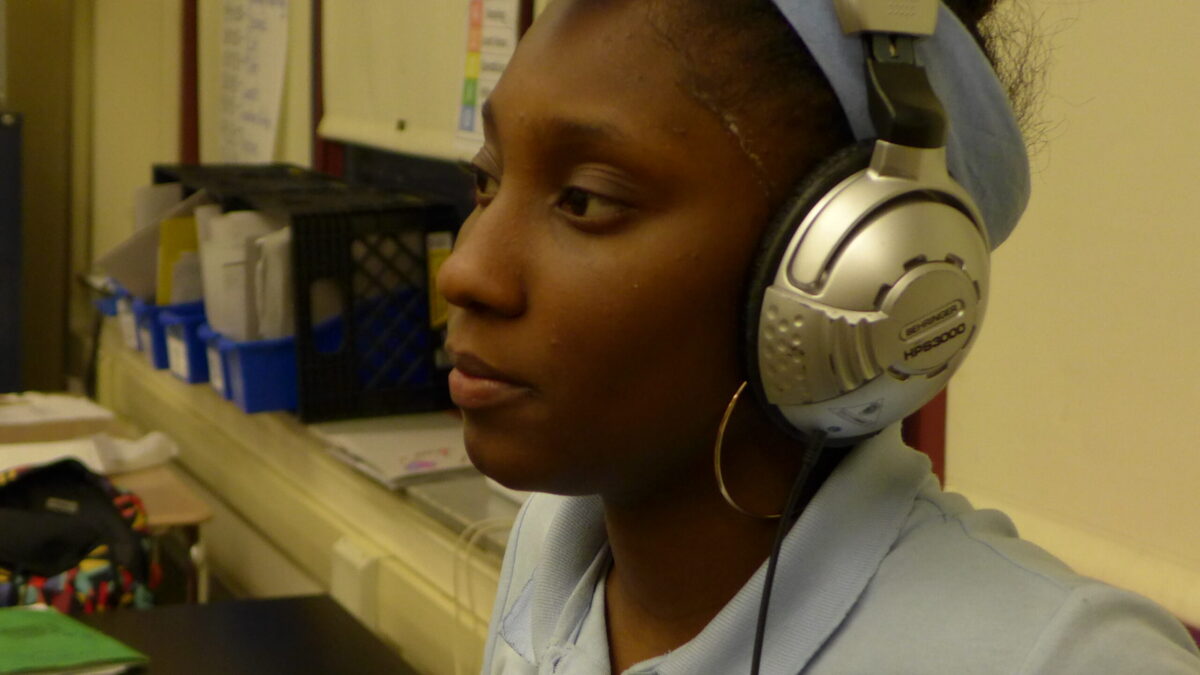 A youth wearing headphones sitting in a classroom