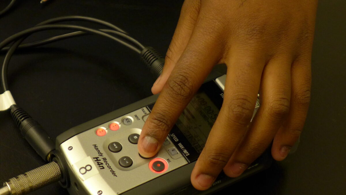 A hand interacting with a portable recorder