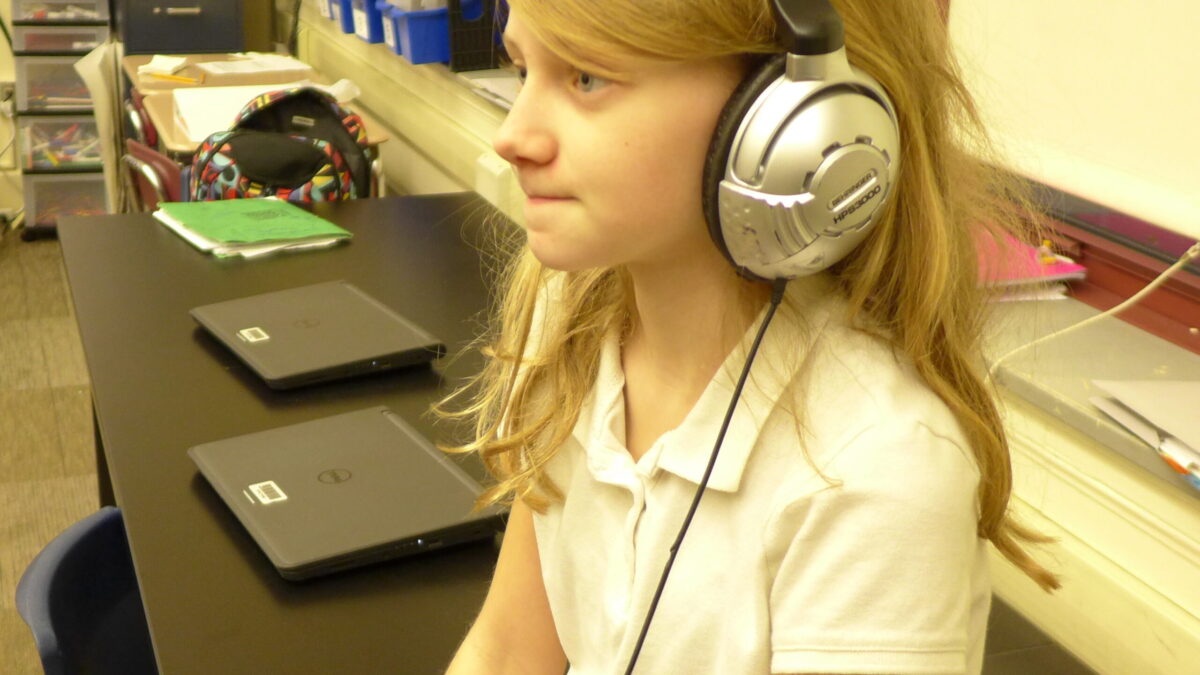 A youth wearing headphones sitting in a classroom