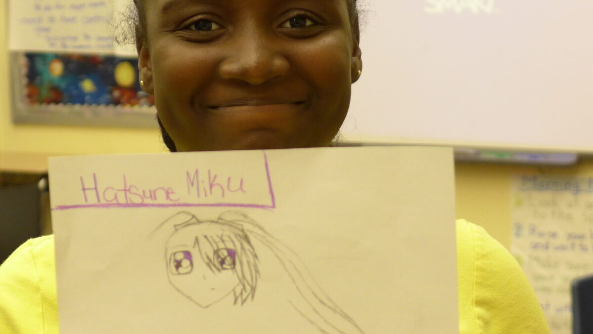 A youth holding up a piece of paper in a classroom
