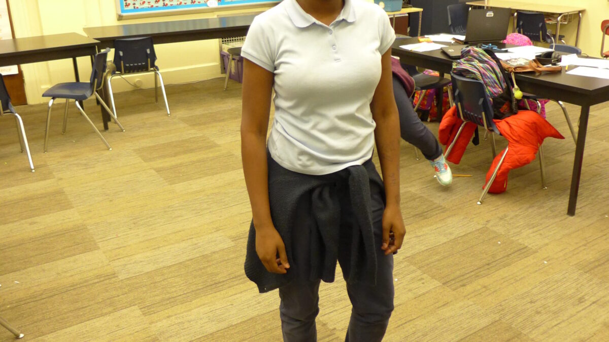 A youth facing the camera standing in a classroom