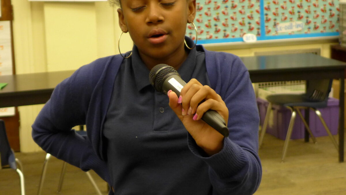 A youth speaking into a microphone in a classroom
