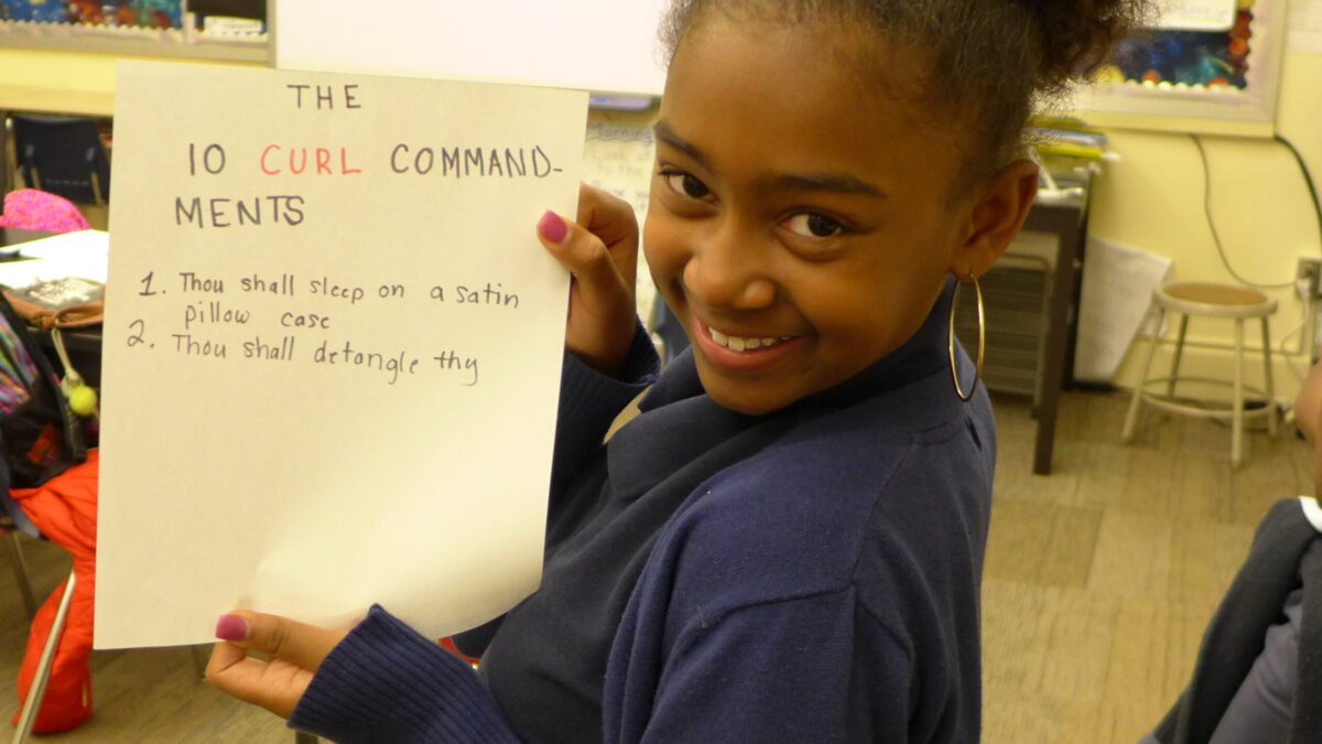 A youth smiling and holding a piece of paper up to a camera