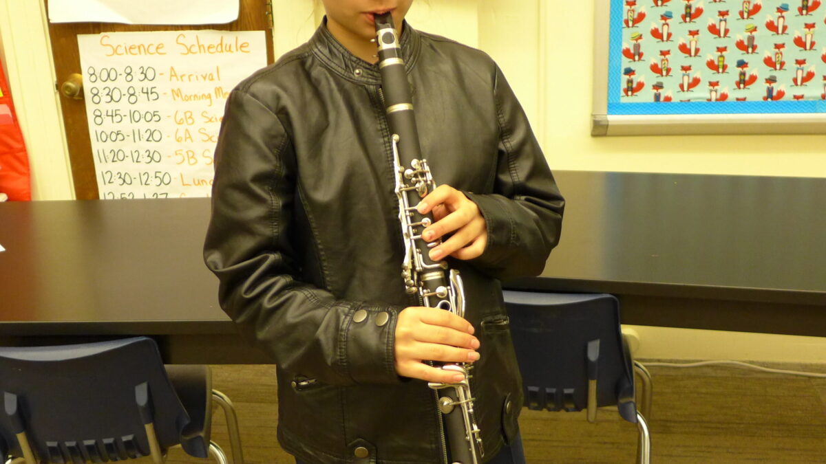 A youth playing a clarinet in a classroom