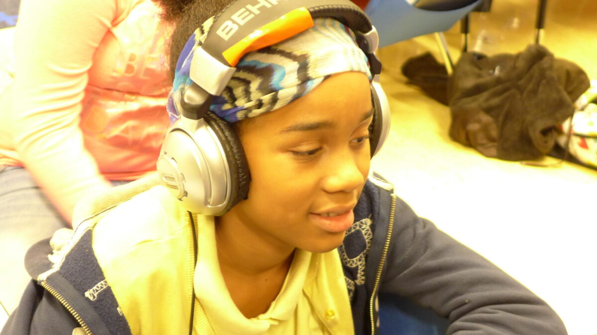 A youth wearing headphones sitting at a classroom desk
