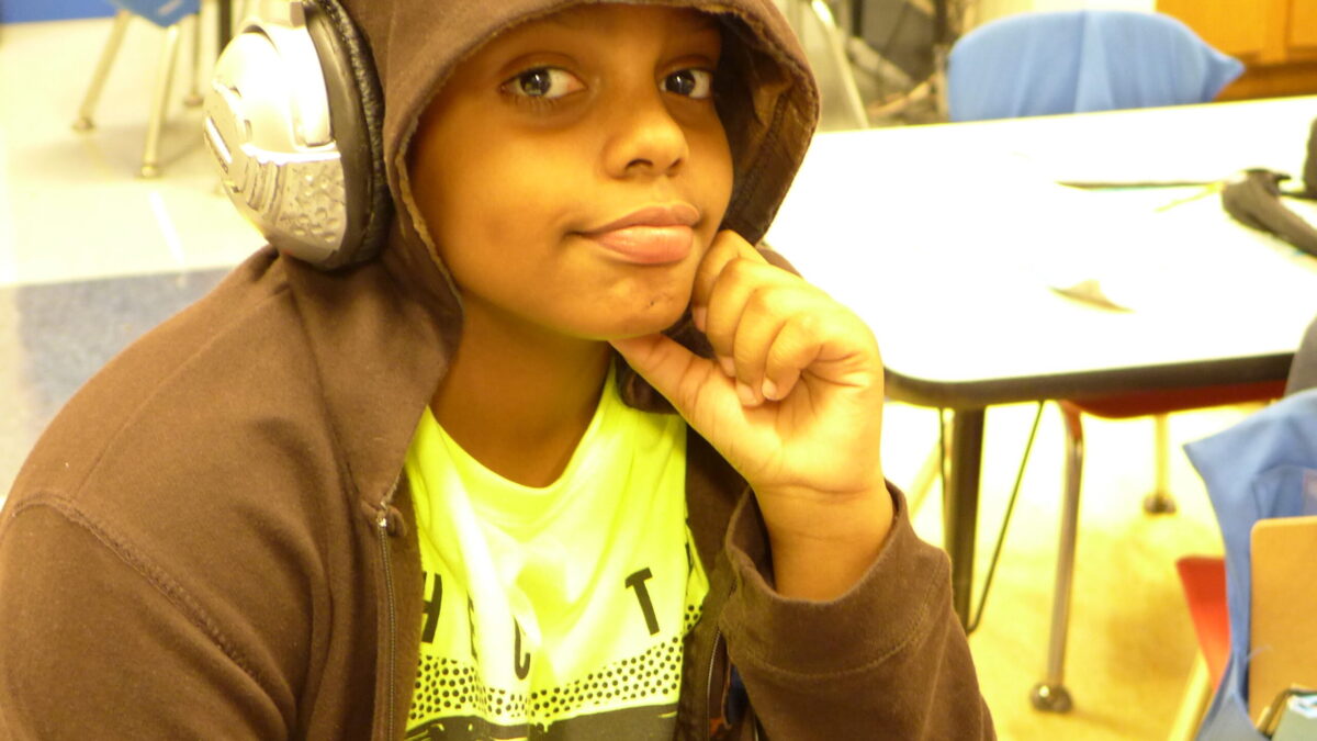 A youth wearing headphones posing in a classroom