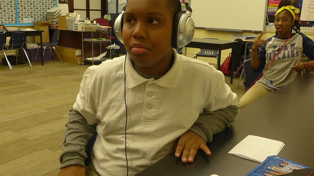A youth wearing headphones sitting in a classroom
