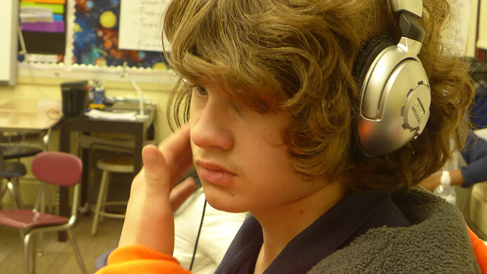 A youth wearing headphones in a classroom