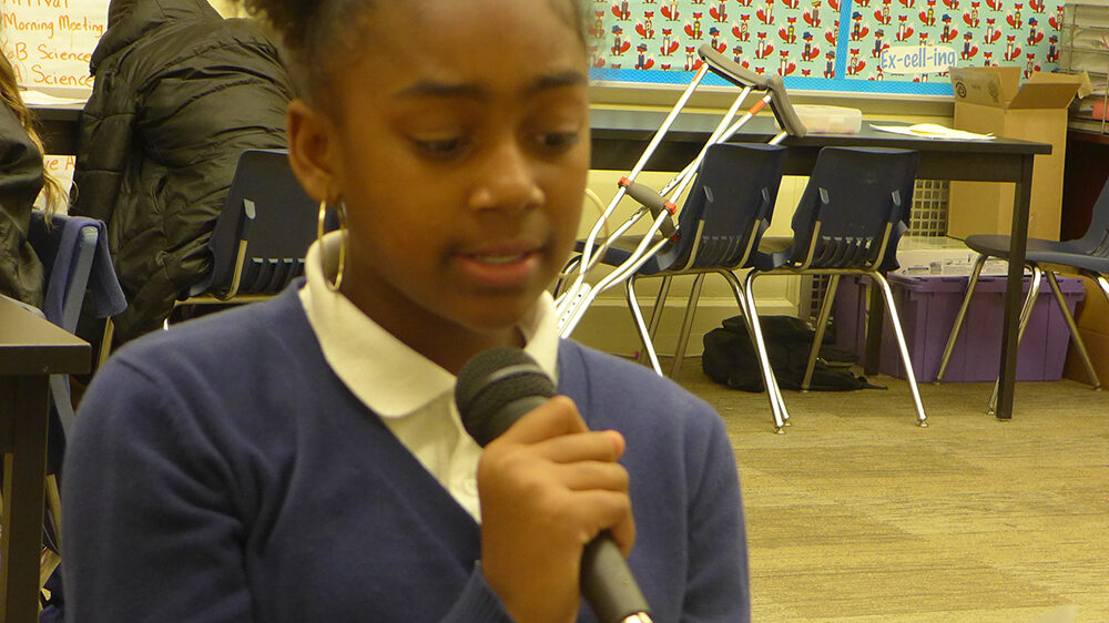 A youth holding a microphone in a classroom