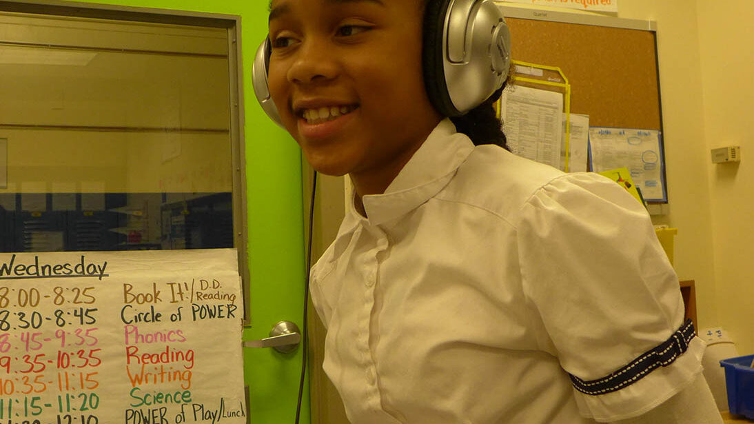 A youth wearing headphones smiling in a classroom