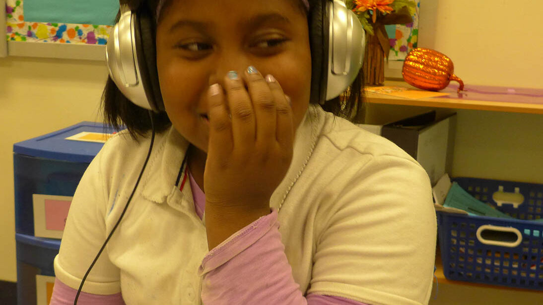 A youth wearing headphones sitting in a classroom