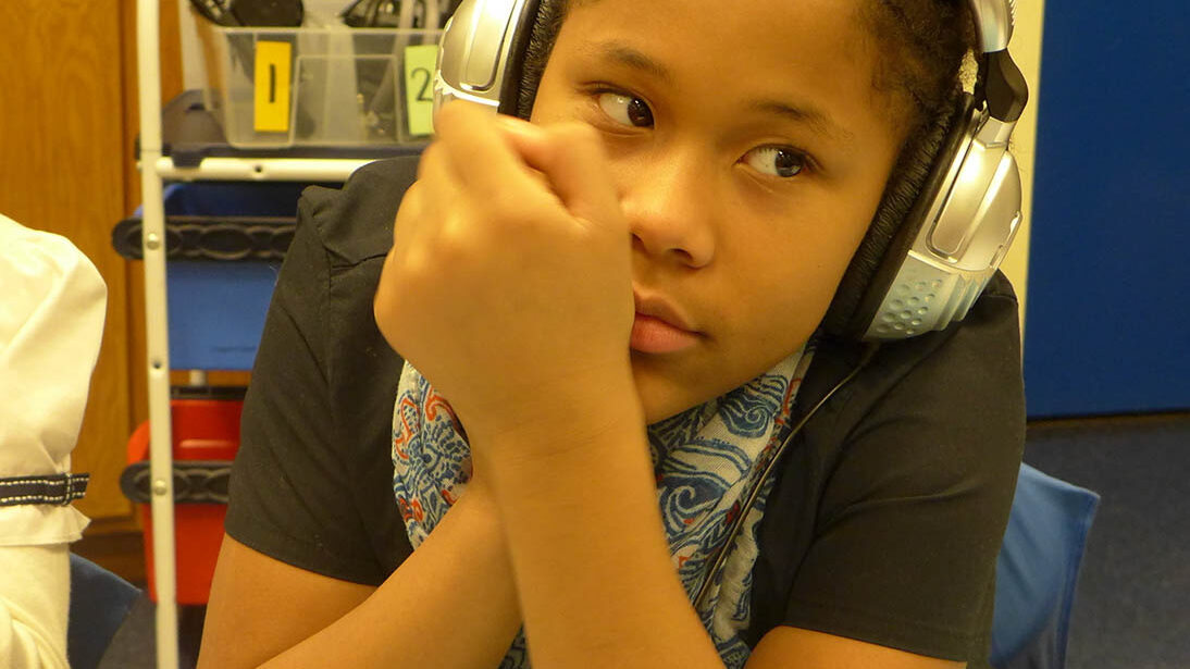 A youth wearing headphones sitting in a classroom