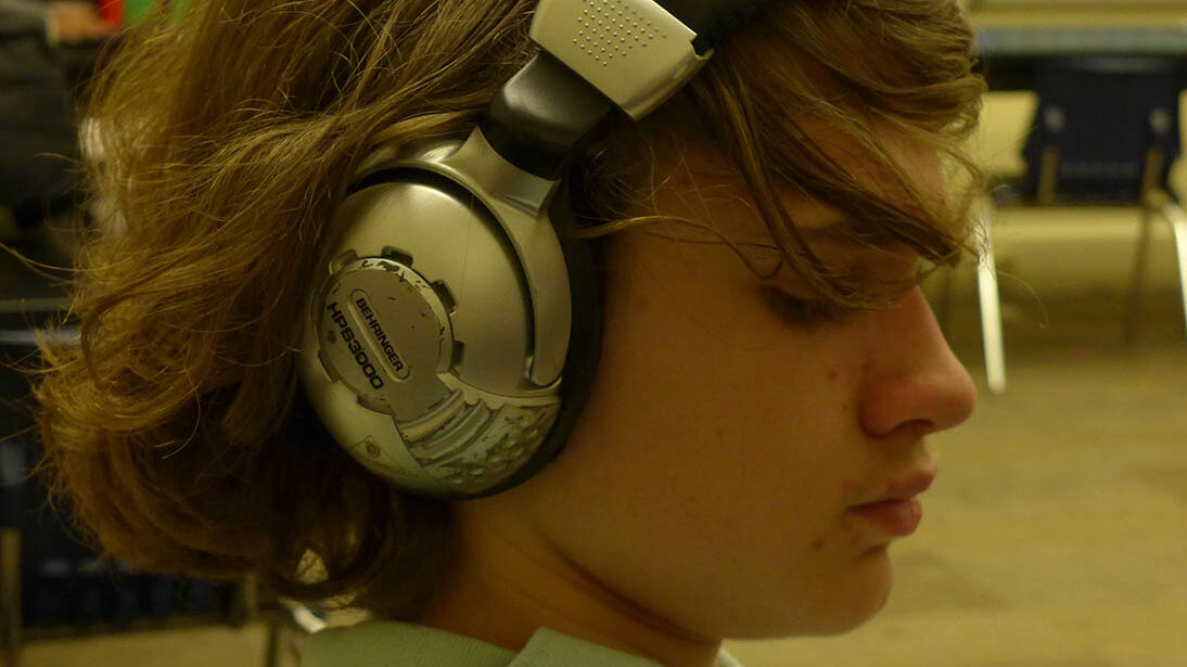 A youth wearing headphones sitting in a classroom