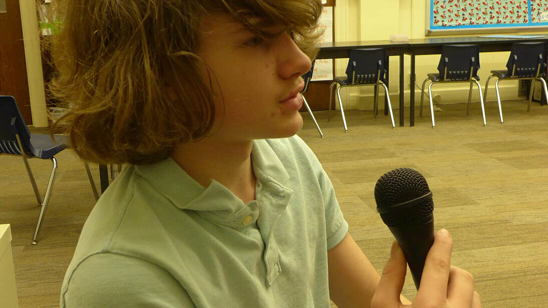 A youth holding a microphone in a classroom
